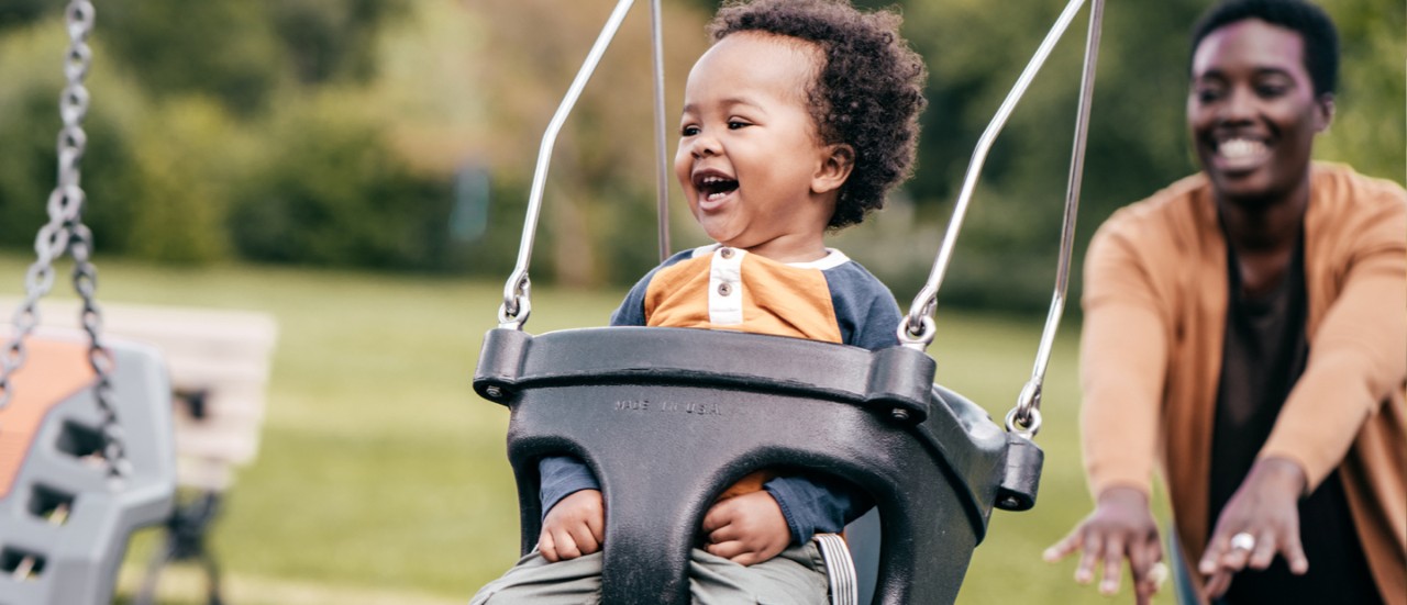 Young mother pushing child on swing