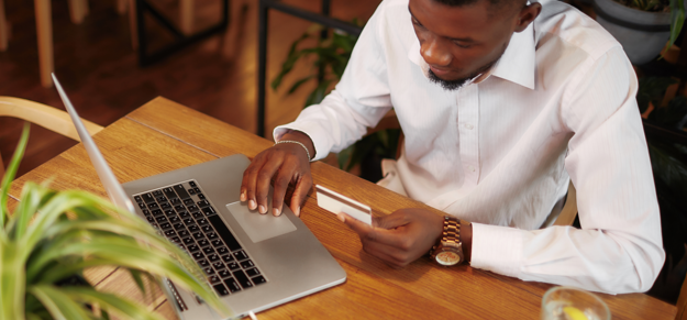 Young male paying on a lap top using a credit card