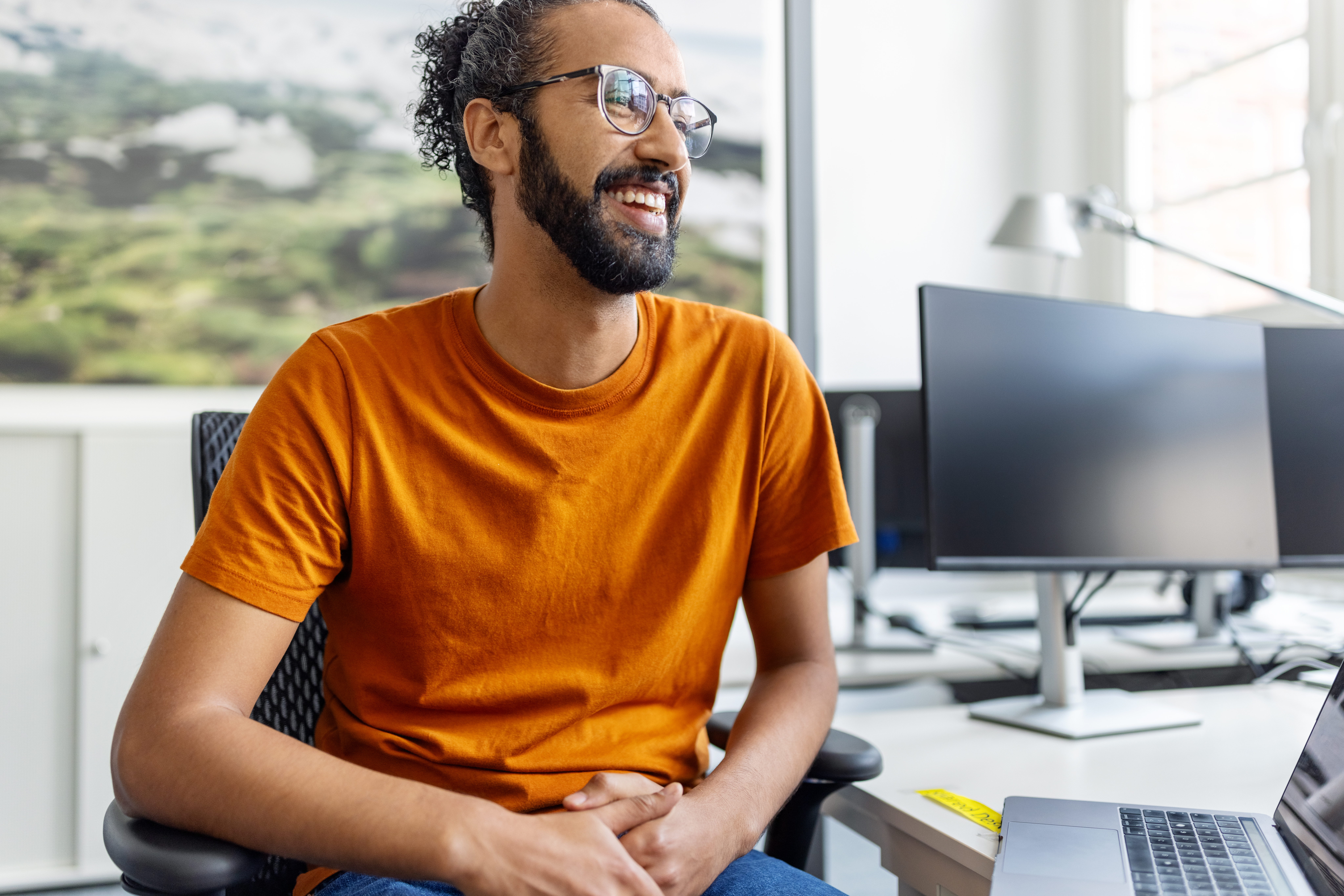 Graduate student smiling at office desk.