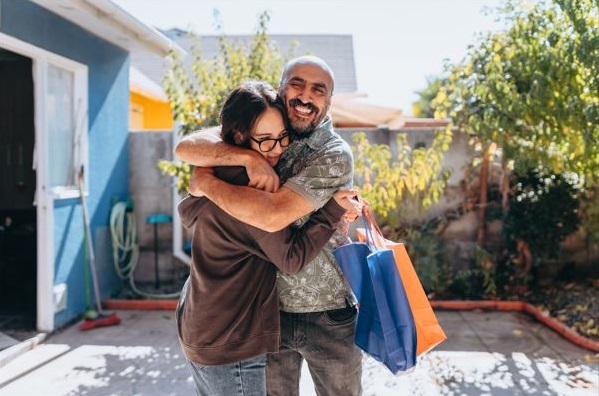 Parent and student hugging in the backyard of a house.
