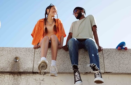 Two students sitting on a high wall.