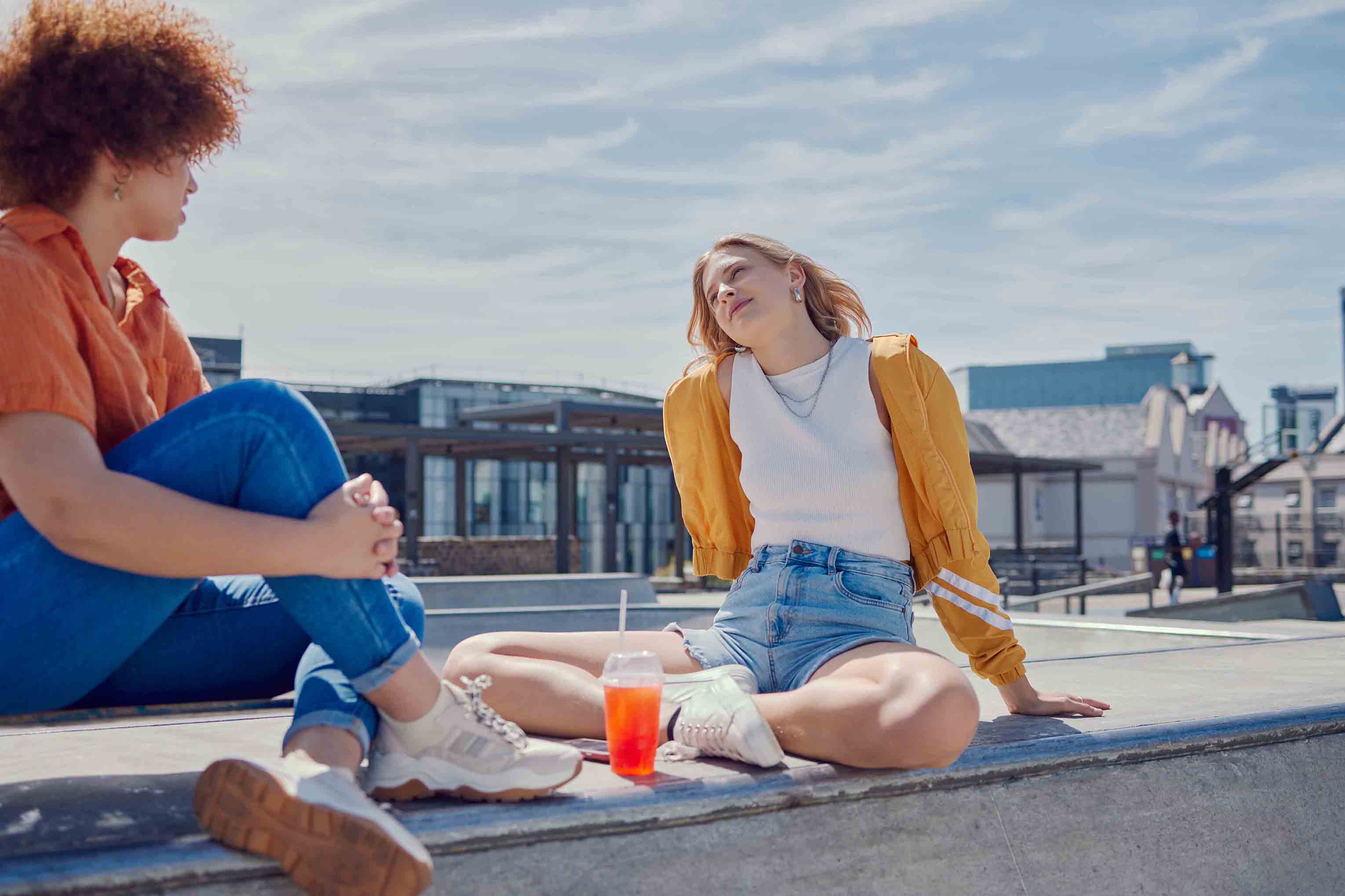 Two people talking outside in the sun.