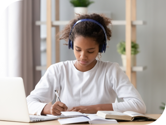 blog cross sell ad photo of a young female girl student sitting at her desk studying with notebooks, headphones, and laptop.