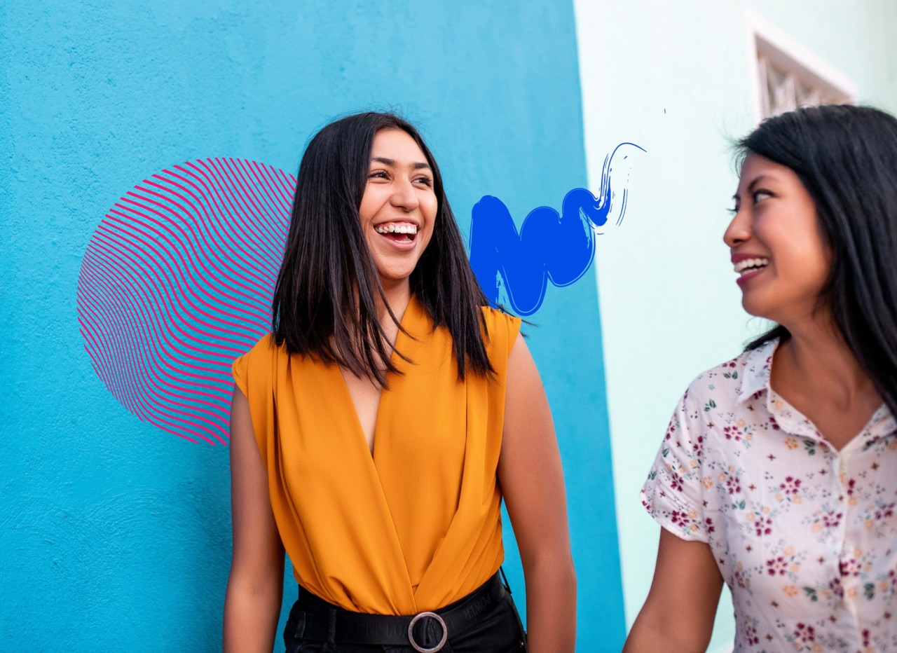 Two friends walking along the side of a building.