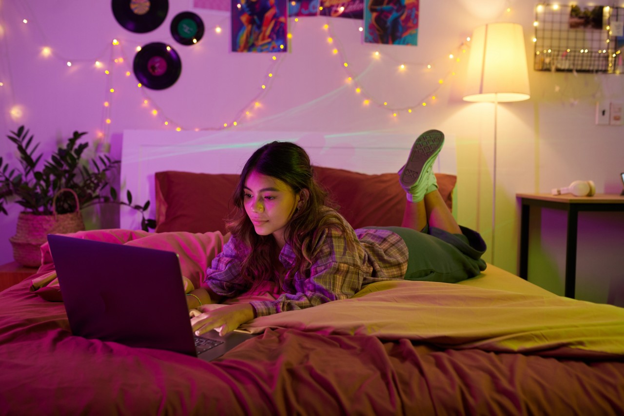 Student in bed on computer.