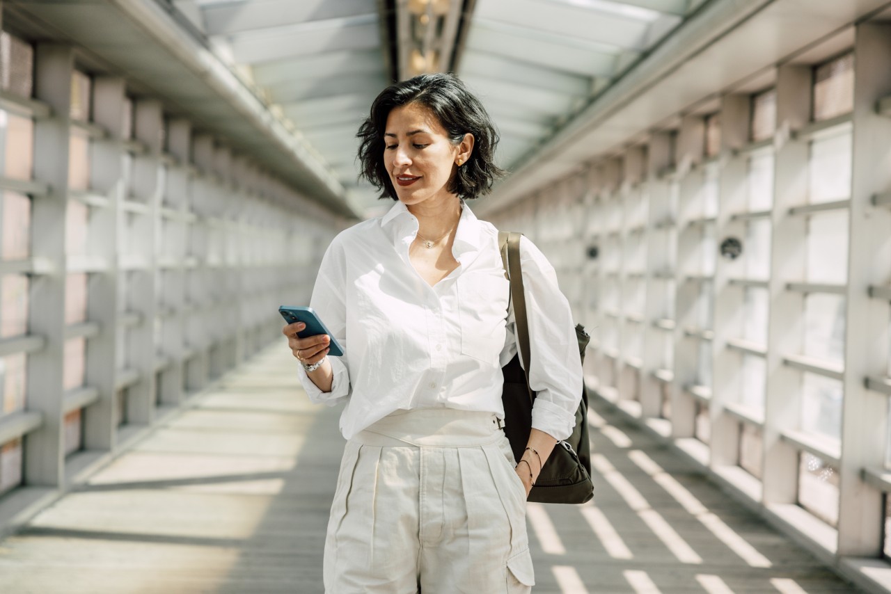 Person walking down raised walkway with phone.